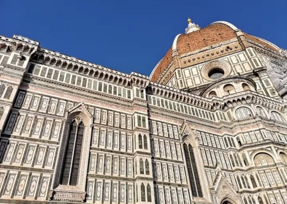 The exterior of Florence Cathedral, showcasing intricate marble patterns and a dome.
