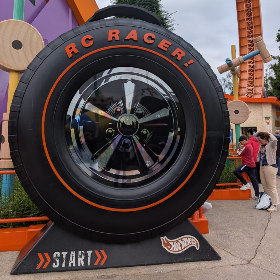 Large decorative tire with "RC Racer" text and a start button, set in a vibrant outdoor area.