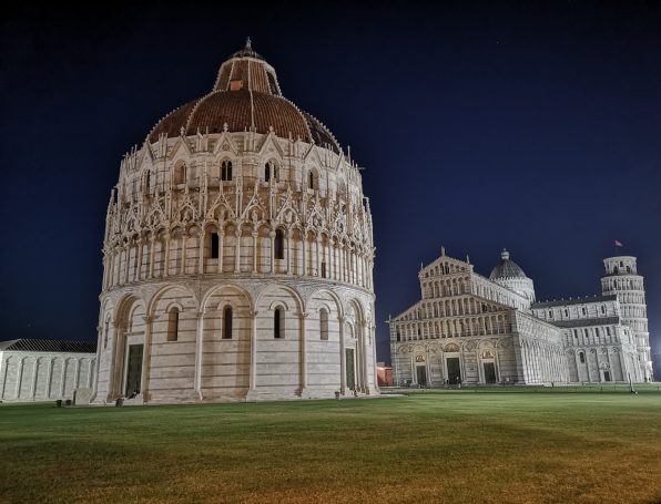Night view of the Pisa Baptistery and Cathedral, showcasing Romanesque architecture.