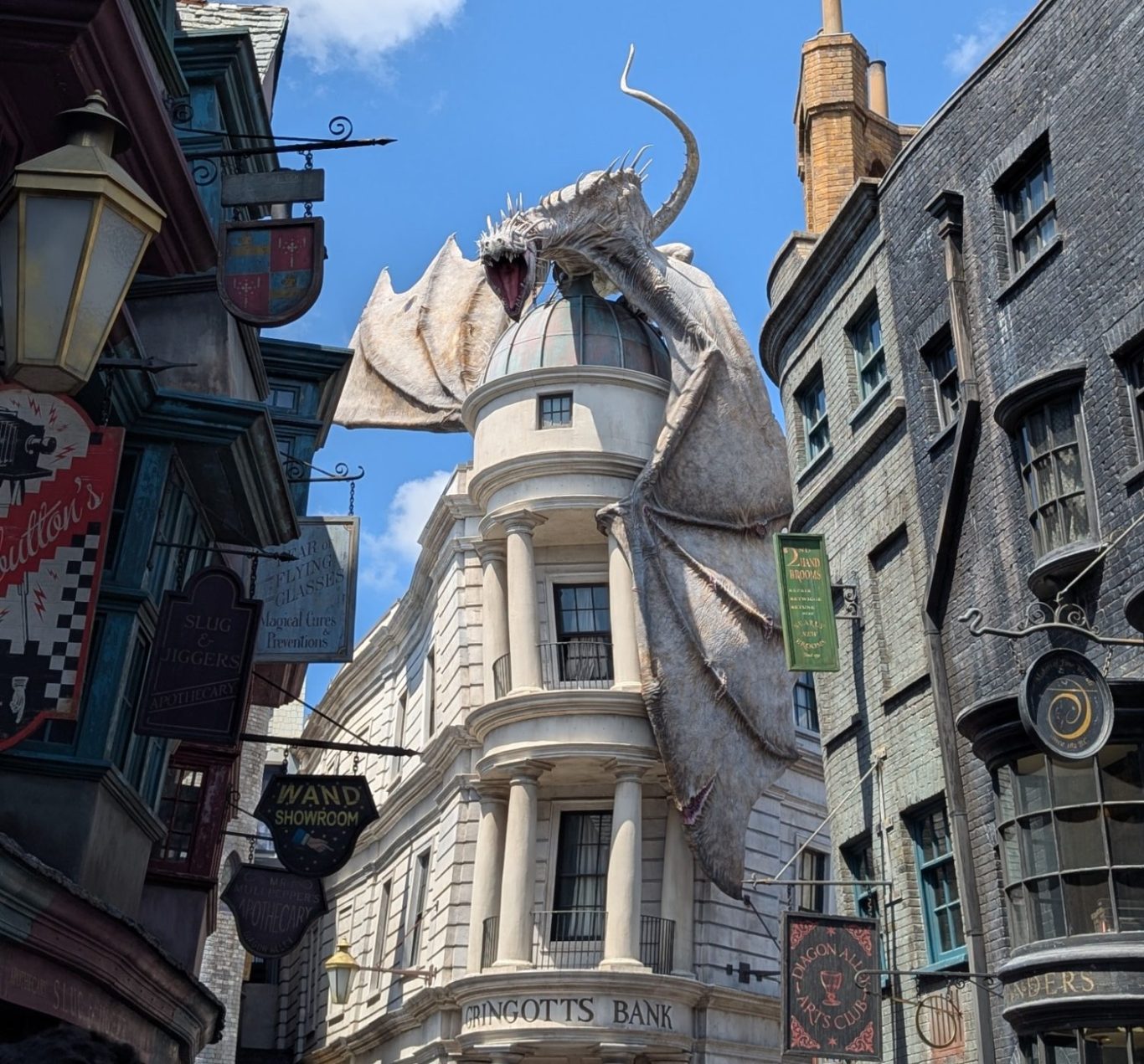 A large dragon atop a white building in a themed street with dark buildings and signs.