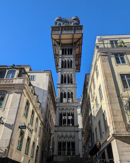 Santa Justa Lift, an historic lift tower surrounded by buildings against a clear blue sky.