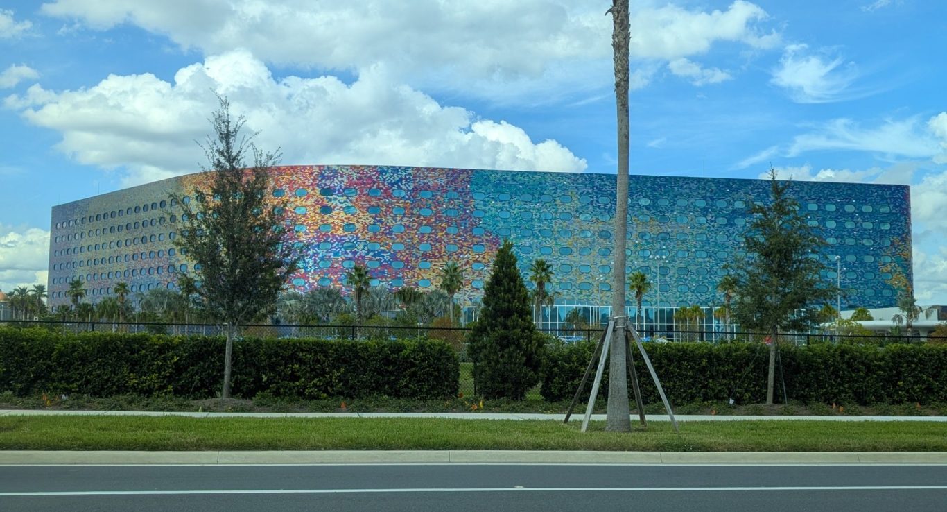 Colourful modern building with palm trees and blue sky in the background.