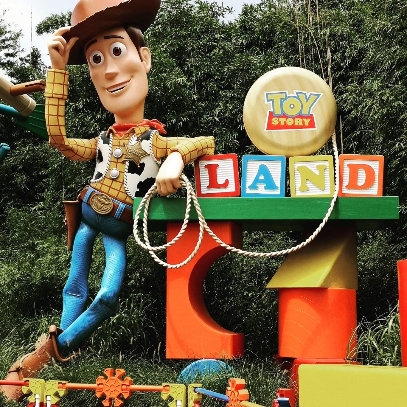 A large Woody figure from Toy Story stands next to a colourful "Toy Land" sign.