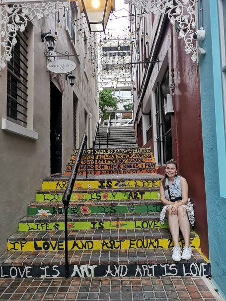 I&B's Founder sitting on the colourful steps located on Chancery Lane in Hamilton, Bermuda.