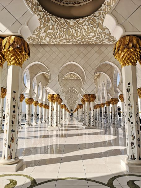 Ornate pillars with golden tops in a grand architectural space, creating a serene atmosphere.