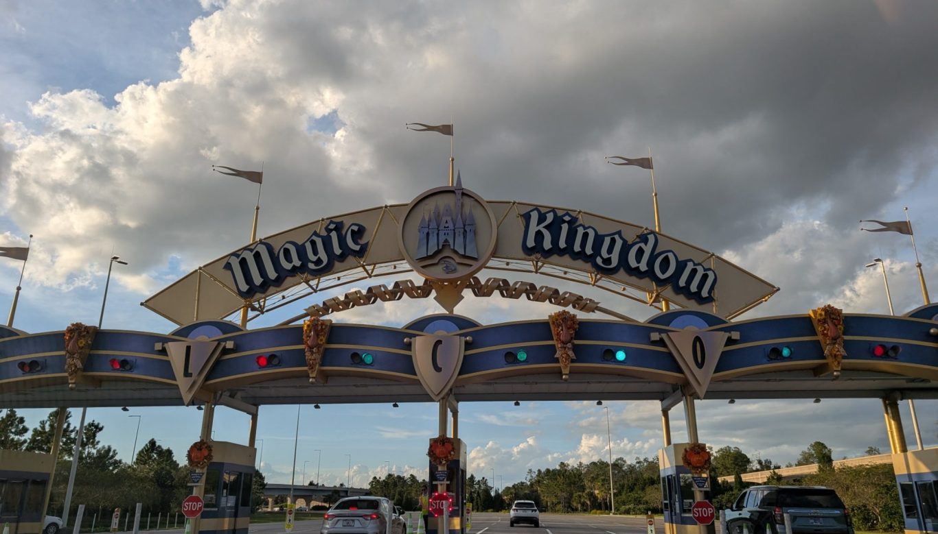 Entrance sign to Magic Kingdom with blue sky and clouds in the background.