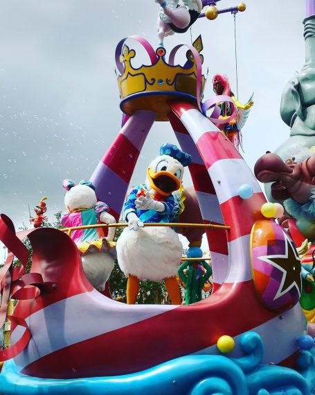 Donald Duck on a colourful float, surrounded by other characters at a parade.