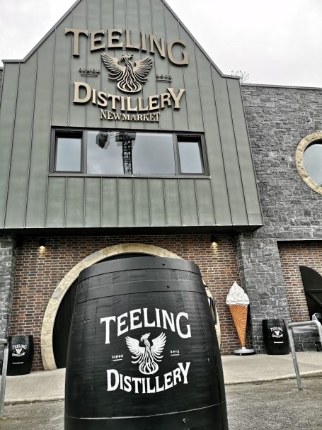 Exterior of Teeling Distillery with a large wooden barrel in the foreground.
