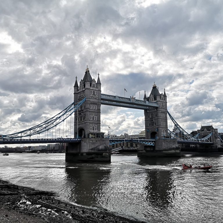 Tower Bridge spanning the River Thames, under a cloudy sky.