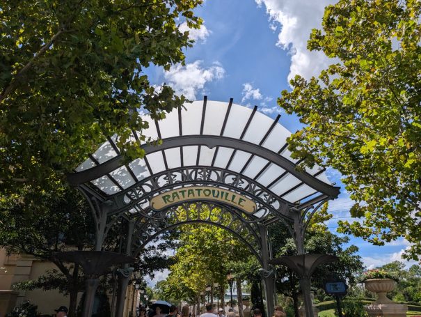 A large, decorative archway with greenery and blue sky in the background.