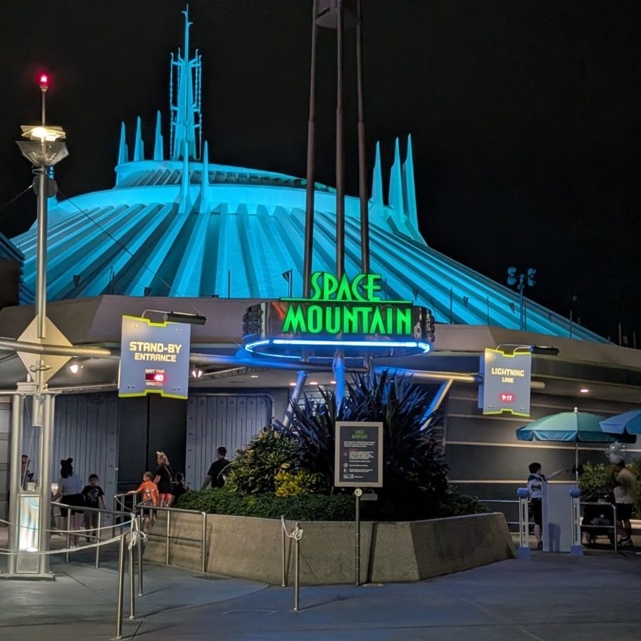Entrance to Space Mountain with illuminated blue structure at night.
