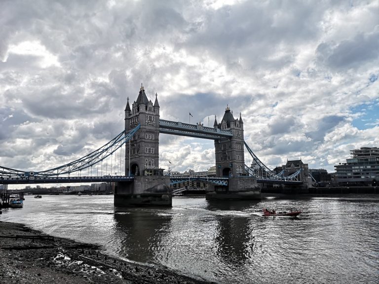 Tower Bridge spanning the River Thames, under a cloudy sky.
