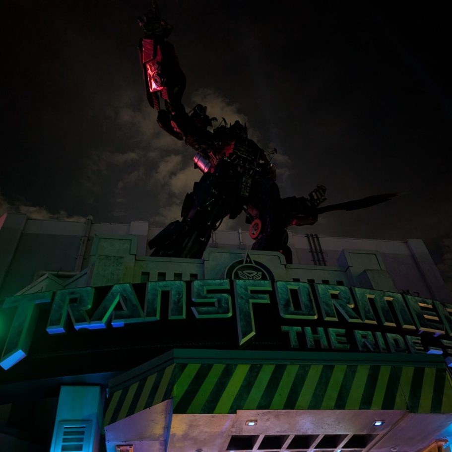A large robotic figure on a building, illuminated with vibrant colours at night.