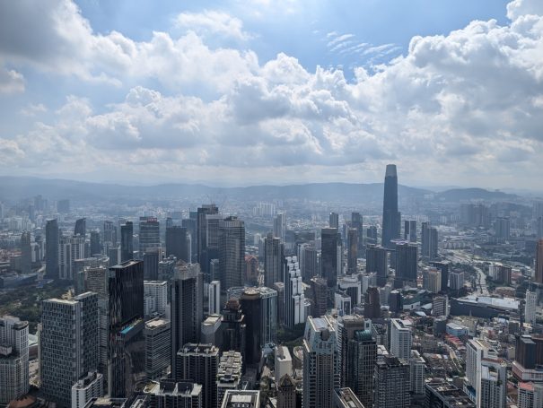 Panoramic view of a bustling Kuala Lumpur city skyline under a cloudy sky.