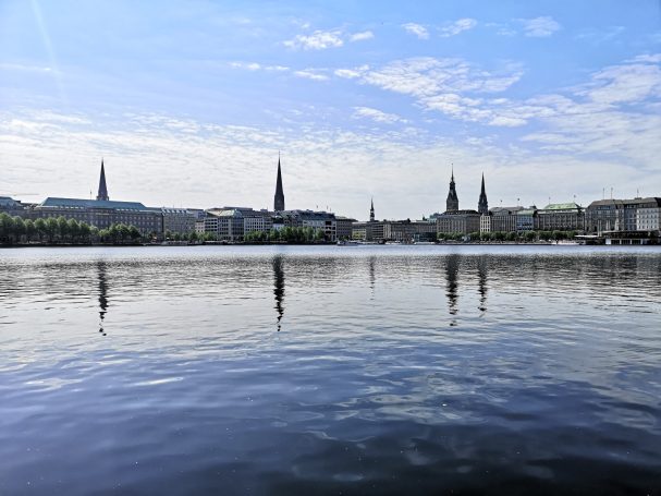 Skyline featuring spires and reflections on calm water.