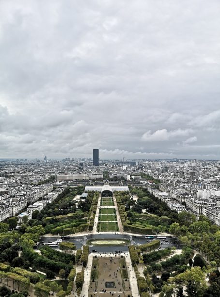 Panoramic view of Paris with green gardens and cloudy skies, from the top of the Eiffel Tower