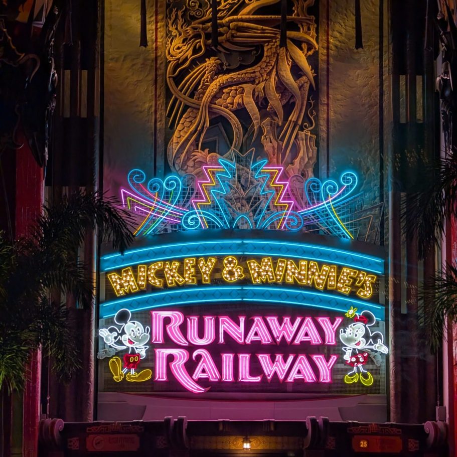 Neon sign for Mickey & Minnie's Runaway Railway with vibrant colours and decorative elements.