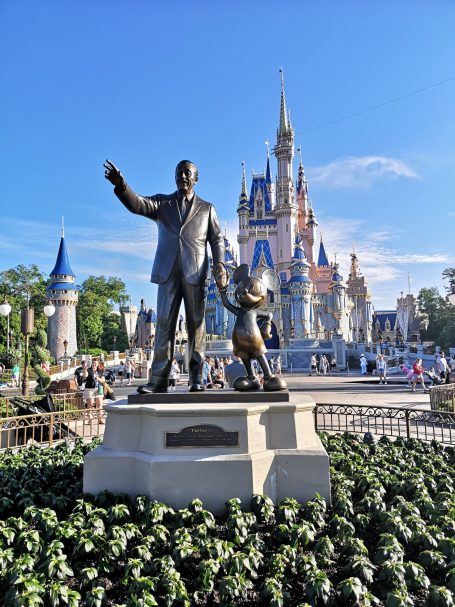 Statue of Walt Disney and Mickey Mouse in front of a fairytale castle.