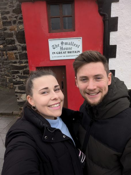 I&B's Founder and Husband posing in front of the smallest House in Great Britain.