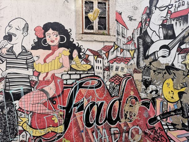 A vibrant mural depicting Fado musicians and a woman in traditional attire with urban scenery in Lisbon.