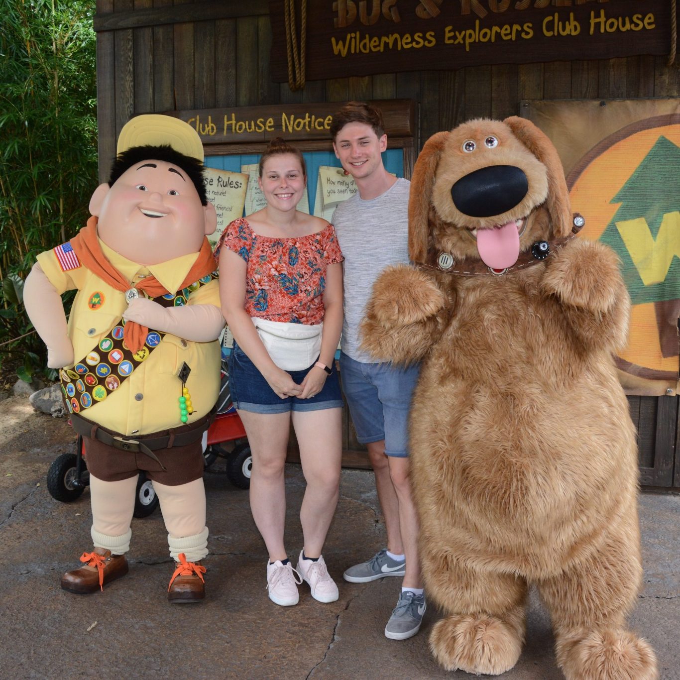 A boy in scout attire, a couple, and a large animated dog posing together.