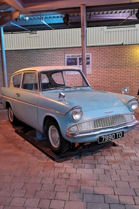 Vintage blue car parked indoors on a tiled surface. Located at the Harry Potter Studio Tour, London.