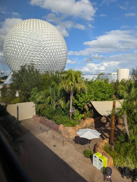 Large geodesic sphere structure surrounded by lush greenery and a clear blue sky.