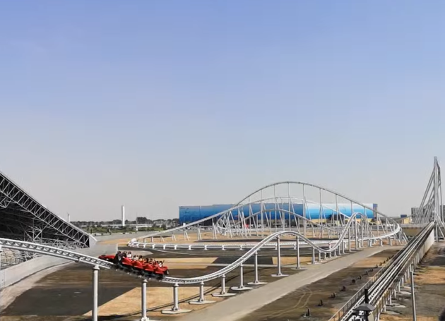 Red roller coaster on a track with blue structures in the background.