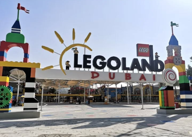Entrance to Legoland Dubai, featuring colourful brick structures and a sunny sky.