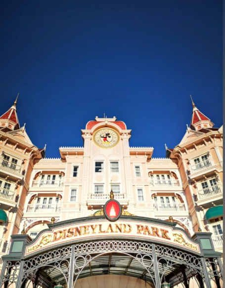 Disneyland Paris Park entrance showcasing ornate architecture against a clear blue sky.