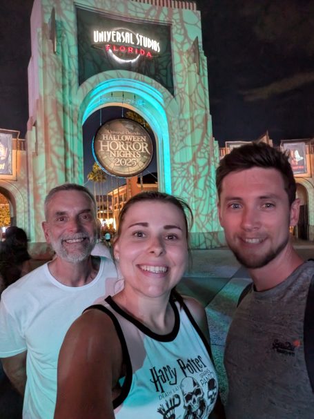 I&B's Founder, Husband & Dad outside of the archway entrance to Universal Studios Florida which is lit up in blue for HHN