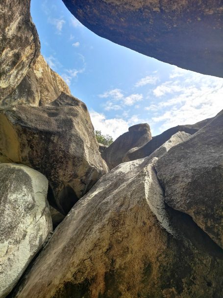 View of large boulders, known as The Baths, with a blue sky and clouds above, creating a natural frame, located at Virgin Gorda.