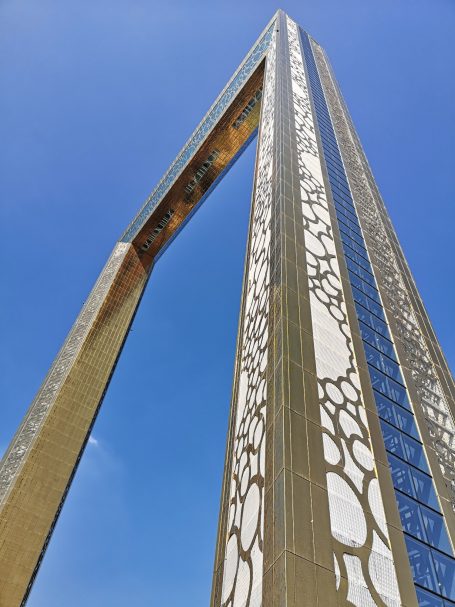 Tall, modern archway structure, known as the Dubai Frame against a clear blue sky.