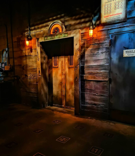 A rustic wooden door in a dimly lit room, with vintage lighting and shadows. The loading area for Tower of Terror ride at Disneyland Paris
