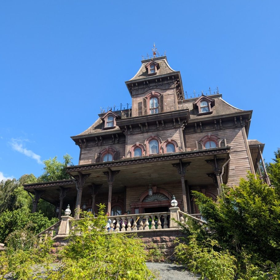 A grand, historic mansion with multiple levels and ornate architecture against a clear blue sky.