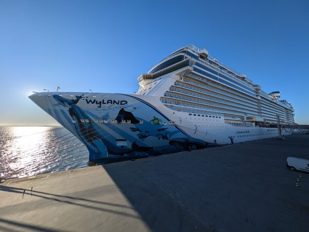 The NCL Bliss cruise ship docked at the harbour in Lisbon with a clear blue sky in the background.