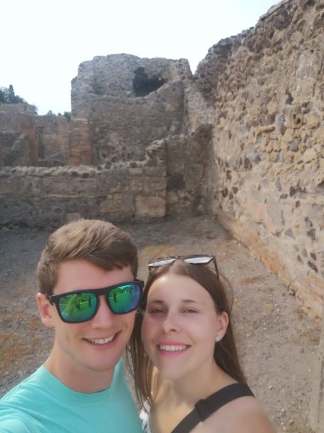I&B's Founder & Husband posing together with ancient ruins of Pompeii in the background. Bright sunny day.