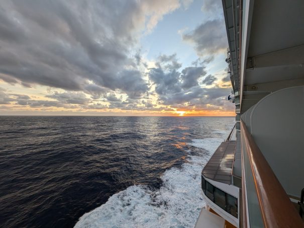 Sunset over the ocean, viewed from the side of a cruise ship.