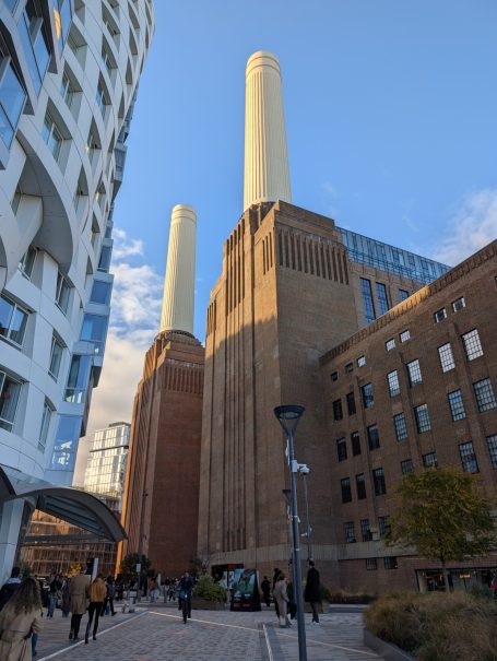 View of Battersea Power Station with its iconic chimneys, surrounded by modern buildings.