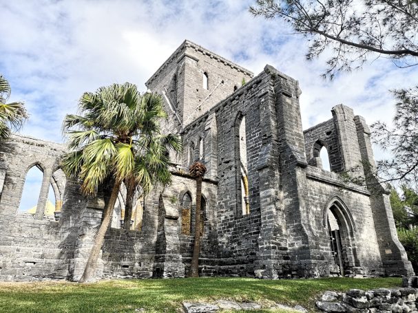 Ruined stone building, known as the Unfinished Church surrounded by palm trees under a cloudy sky, located in St George's Bermuda.