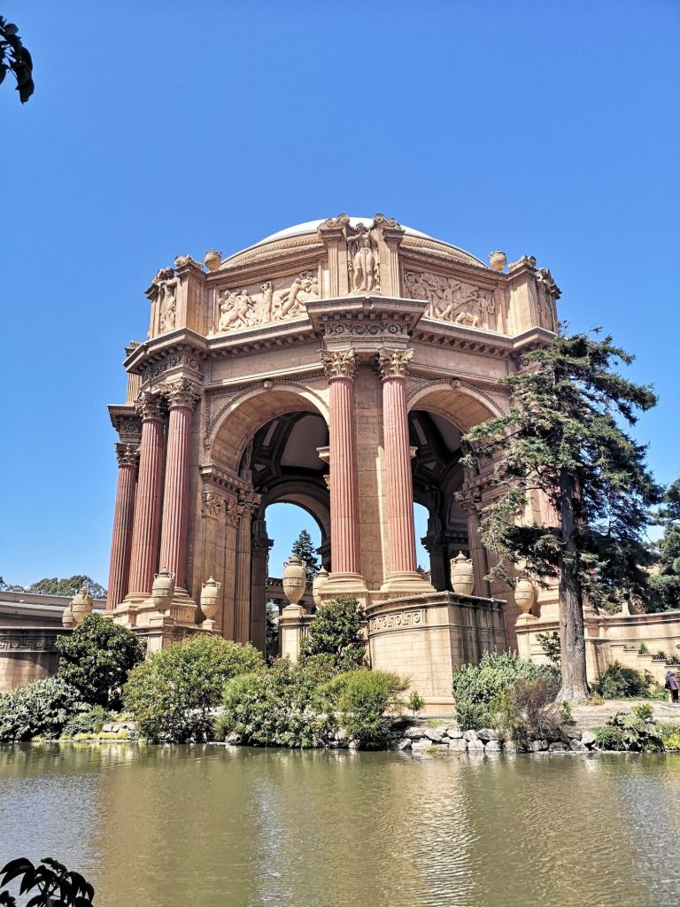 Classical architecture structure with columns, surrounded by greenery and water.