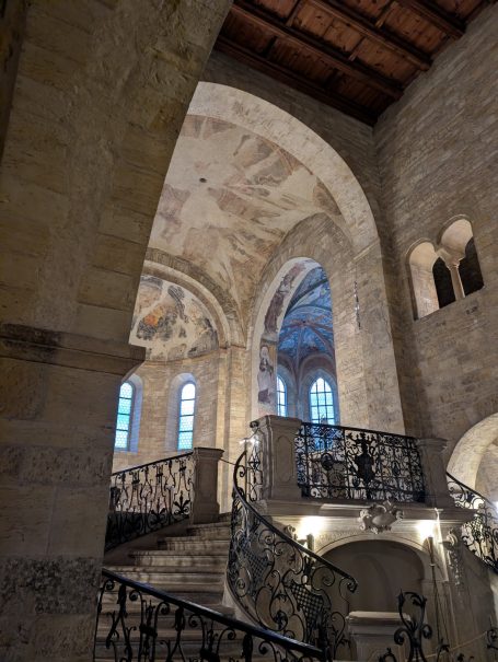 Interior of a stone building featuring arched ceilings and a decorative staircase.