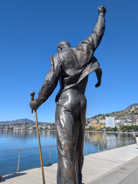 Bronze statue of Freddie Mercury raising his fist, overlooking Lake Geneva and Montreux.