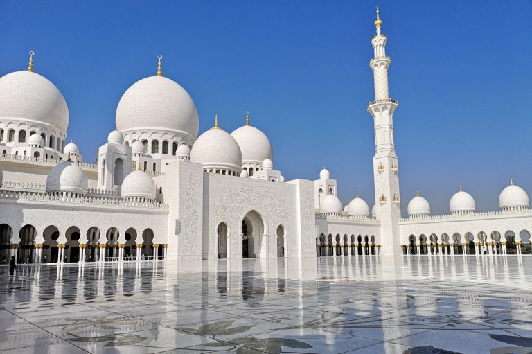 Sheikh Zayed Grand Mosque with white domes and minaret against a clear blue sky in Abu Dhabi