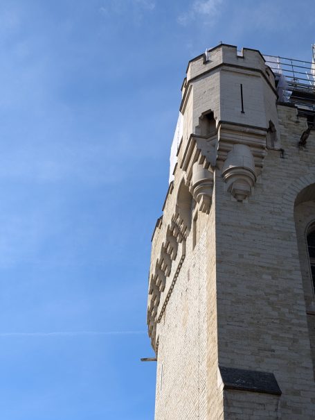 Close-up of the Halle Gate stone tower with decorative elements against a clear blue sky.
