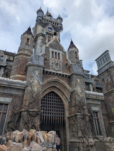 Gothic castle with stone façade and intricate architectural details under a cloudy sky.