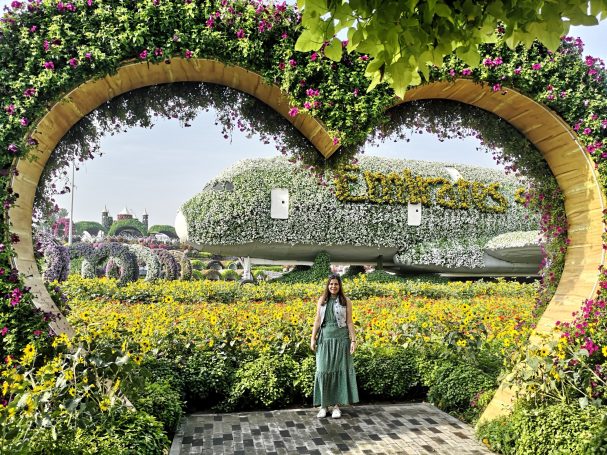 I&B's Founder posing in front of the Emirates A380 airplane covered in blooming flowers, framed by a heart archway with greenery surrounding