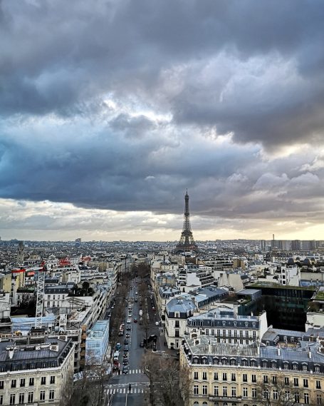 View of Paris skyline with the Eiffel Tower under a cloudy sky.