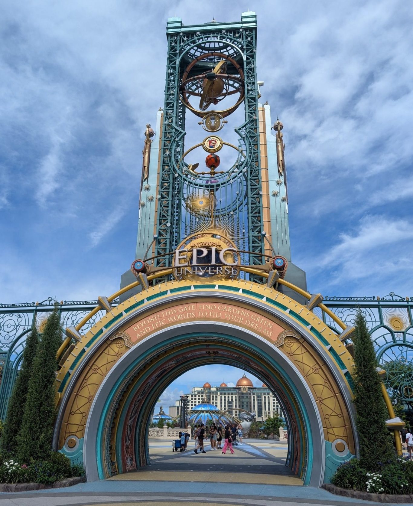 Ornate archway with intricate details and clock, under a blue sky.