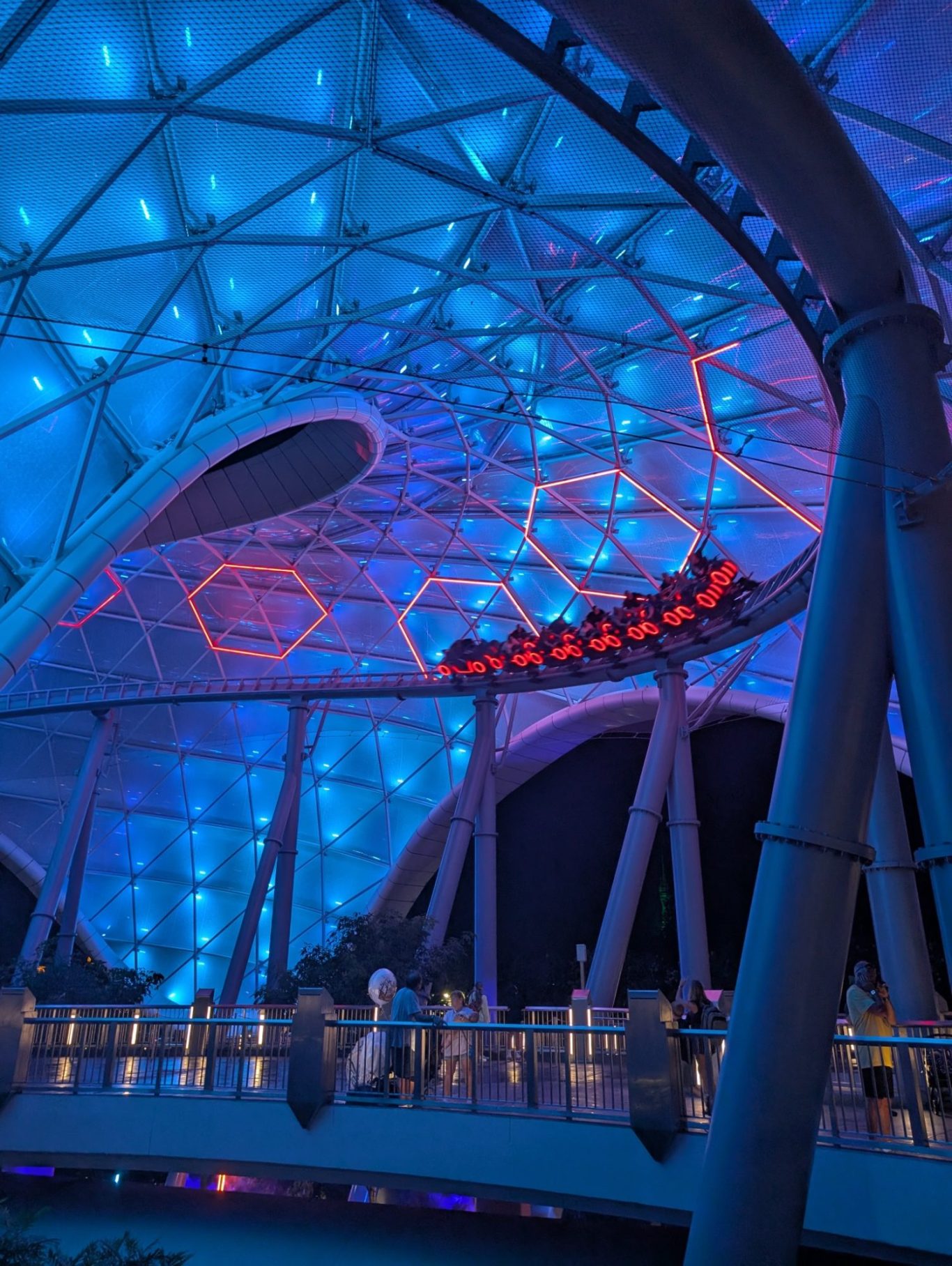 Illuminated ceiling with hexagonal patterns and vibrant blue lighting in a modern structure.